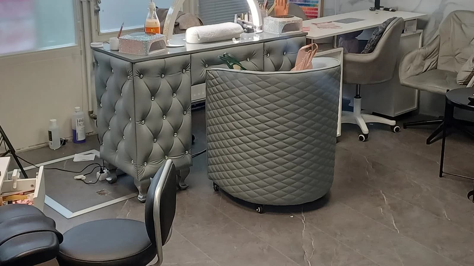Interieur van Mercy Nail Studio met manicuretafels en grijze fauteuils